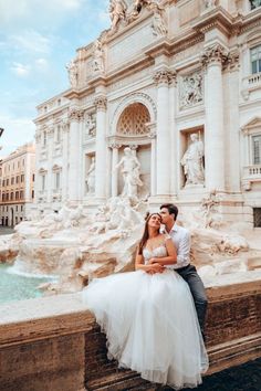 a bride and groom are sitting on a wall in front of the trello dei duoo