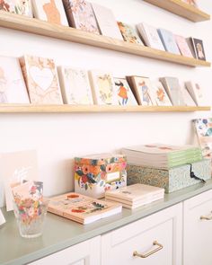 many cards are on the counter in front of some shelves with pictures and greeting cards