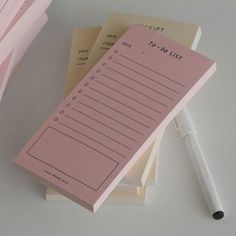 a pink notepad sitting on top of a pile of papers