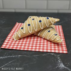 two pieces of bread sitting on top of a red and white checkered napkin