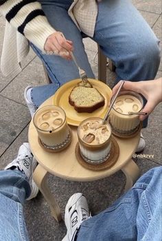 two people sitting at a table with desserts on it and one holding a fork