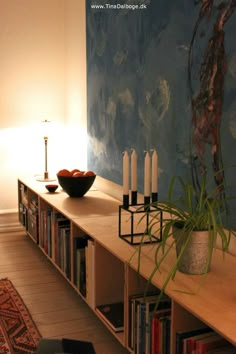 an image of a table with candles and books on it in front of a painting