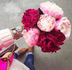 a woman holding a bouquet of pink and red flowers in her hand, on the ground