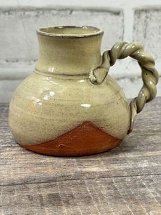 a brown and white vase sitting on top of a wooden table