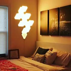 a bed sitting under a light next to a window in a room with two pictures on the wall