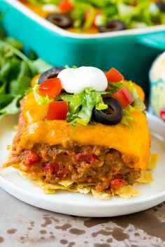 an enchilada casserole on a plate with lettuce and tomatoes