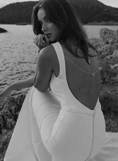 a woman in a white dress sitting by the water