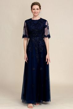 a woman in a long blue dress with sheer sleeves and an embellishment on the shoulders