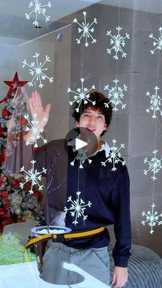 a man standing in front of a christmas tree with snowflakes on the wall