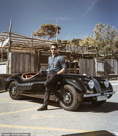 a man sitting on top of an old fashioned car