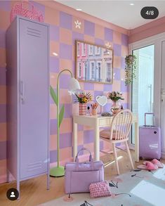 a room with pink and purple wallpaper, a white chair, desk and suitcases