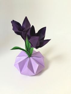 an origami vase with purple flowers in it