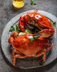 two large crabs on a plate with lemon wedges and parsley leaves, ready to be served