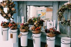 several white buckets filled with flowers and plants