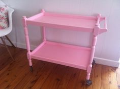 a pink cart sitting on top of a hard wood floor next to a white wall