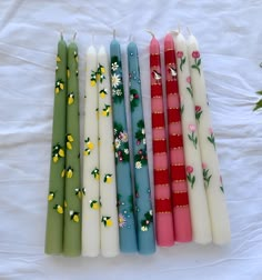 flower pattern Set of 2 taper candle. size 26*2.2 cm Model numbers are written under the candles Candle Paint Design, Painted Pillar Candles Diy, Hand Painted Candle Sticks, Tapered Candle Painting, Painted Tapered Candles, Painting Candle Sticks, Painting Taper Candles, Taper Candle Painting, Hamper Inspiration