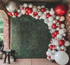 a balloon arch is decorated with red, white and silver balloons in the shape of an elephant