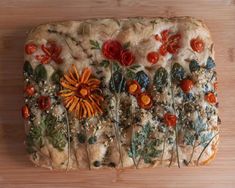 a square shaped pizza with flowers and herbs on it