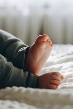 a baby laying on top of a bed with his feet propped up in the air