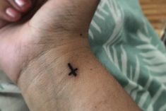 a small cross tattoo on the wrist