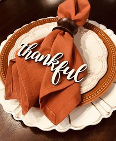 a napkin with the word grateful on it sitting on top of a white and brown plate