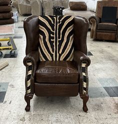 a brown leather chair with zebra print on the back and arms, in a warehouse