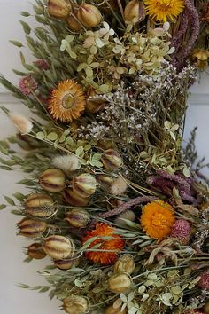 a wreath with dried flowers and leaves hanging on a door