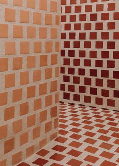 an orange and white tiled bathroom with checkered floor tiles on the walls, and a toilet in the corner