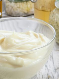 a glass bowl filled with cream sitting on top of a table next to other jars