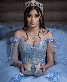 a woman in a blue dress and tiara sitting on the floor