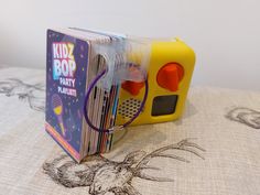 a yellow toy radio sitting on top of a bed next to a book case filled with books