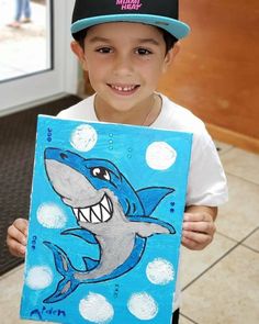 a young boy holding up a drawing of a shark