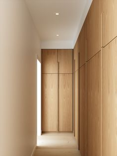 an empty hallway with wooden cabinets and white walls