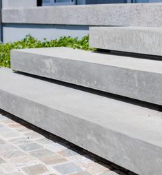 two concrete benches sitting next to each other on top of a brick walkway in front of a building