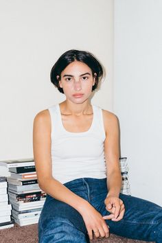 a woman sitting on the floor in front of stacks of books