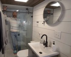 a man is standing in the shower with his hands up and looking at the camera