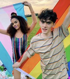 two young people standing next to each other holding kites