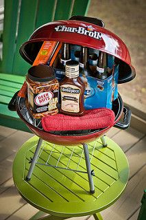 a barbecue grill with various condiments and seasonings in it sitting on a green table