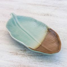 a green and gold leaf shaped dish sitting on top of a wooden table