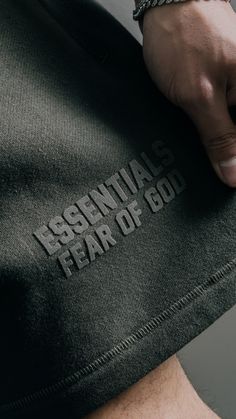 a close up of a person's arm with the words essentials fear of god on it