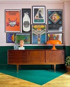 a room with posters on the wall and an orange table lamp in front of it