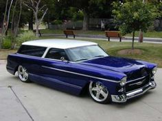 an old blue and white car parked on the street