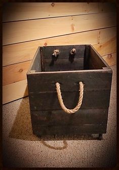 an old wooden box with rope hanging from it's sides on carpeted floor