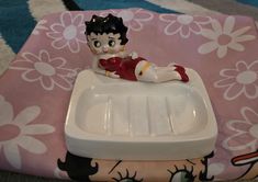 a figurine sitting on top of a white tray next to a pink flowered blanket