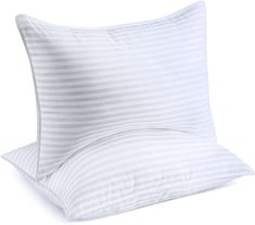 two pillows sitting next to each other on top of a white pillow case with stripes