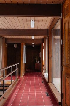 an empty hallway with red tiles and wooden walls