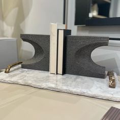 a pair of bookends sitting on top of a marble table next to a mirror