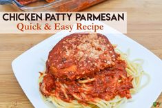 chicken parmesan with sauce and noodles on a white plate, sitting on a wooden table