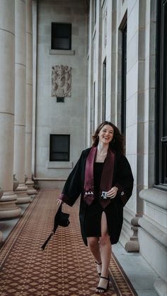 a woman is walking down the hall with an umbrella in her hand and wearing a black coat