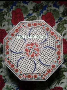 a close up of a white and red plate on a flowery tablecloth with roses